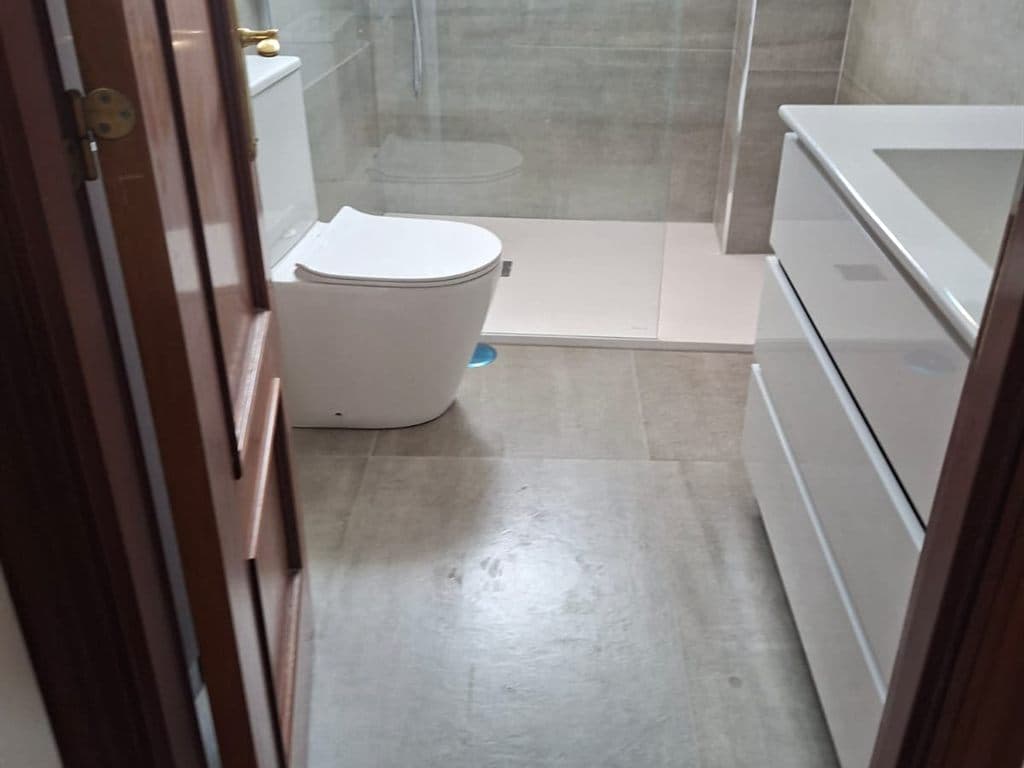 Baño con mampara y mueble de lavabo tras una reforma interior en Vigo
