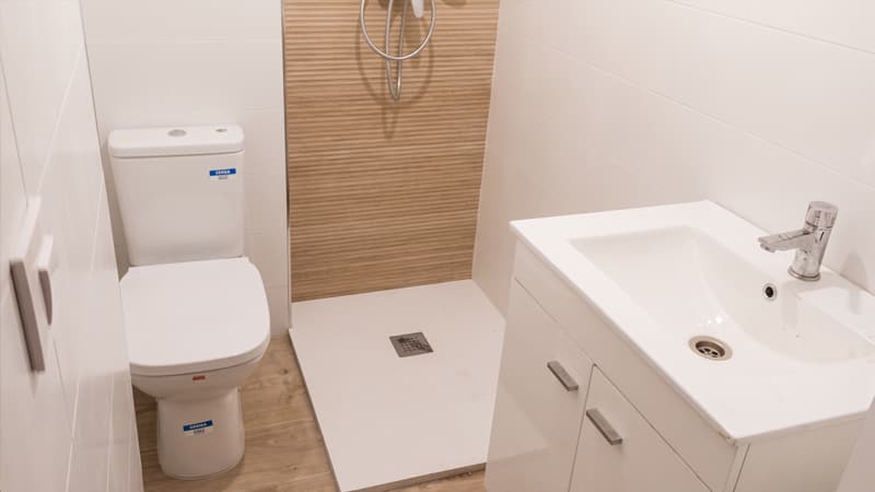 Baño reformado con plato de ducha y revestimiento de madera en Vigo